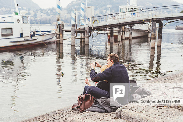 Young couple sitting photographing from lakeside  Lake Como  Italy