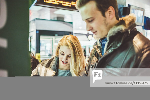 Young couple buying train tickets from ticket machine