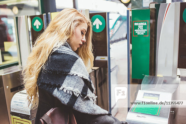 Junge Frau benutzt Fahrkartenschranke im Bahnhof