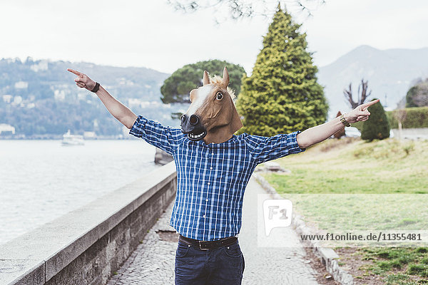 Portrait of man wearing horse mask with arms open  Lake Como  Italy