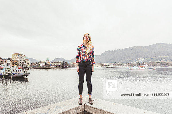 Porträt einer jungen Frau auf einer Hafenmauer stehend  Comer See  Italien
