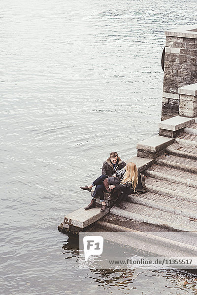 Hochwinkelaufnahme eines jungen Paares  das auf einer Hafentreppe sitzt  Comer See  Italien