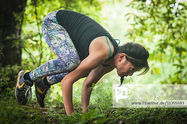 Mid adult woman exercising in forest  doing handstand