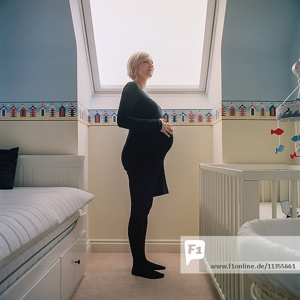 Seitenansicht der schwangeren Frau im Kinderzimmer
