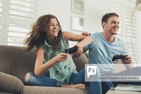 Couple on sofa using video game controller smiling