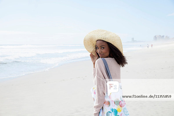 Junge Frau mit Hut am Strand