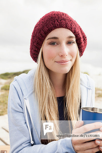 Junge Frau hält Tasse Kaffee an einem kalten Tag