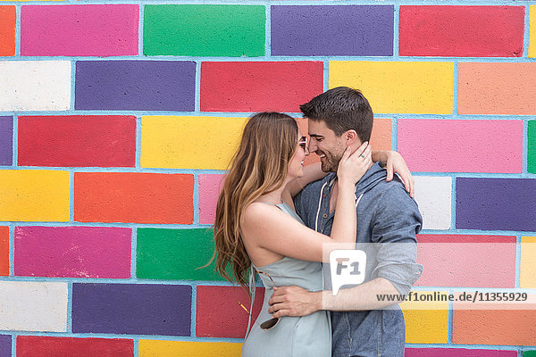 Couple in front of colourful tiled wall hugging  Coney island  Brooklyn  New York  USA