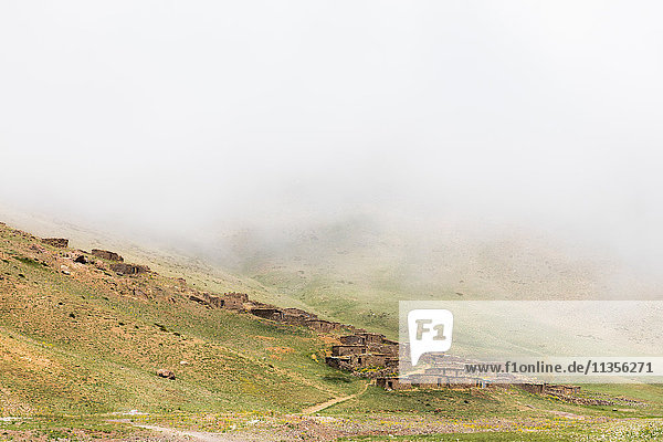 Nebliger Landschaftsblick auf Steinhäuser am Hang  Skigebiet Oukaimeden  Marrakesch  Marokko