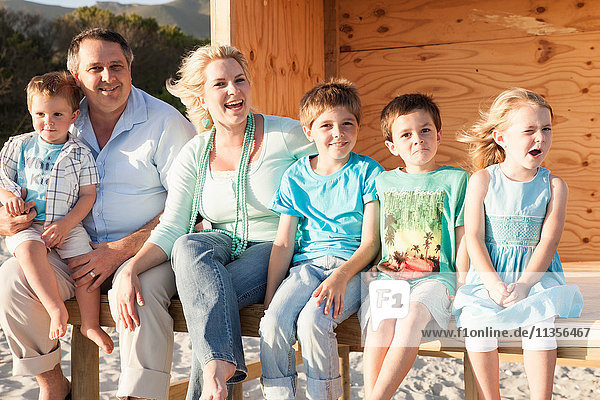 Familie am Strand mit lächelndem Blick auf die Kamera