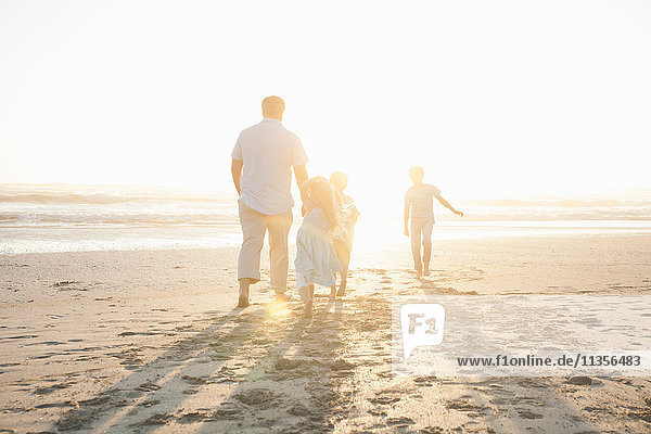 Rückansicht der Familie am Strand beim Spaziergang zum Meer