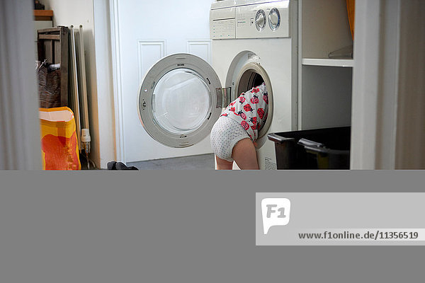 Kleines Mädchen untersucht in Waschmaschine