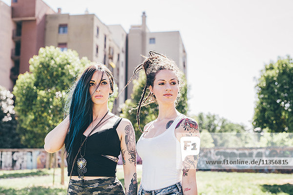 Zwei junge Frauen schauen seitwärts in den Stadtpark.