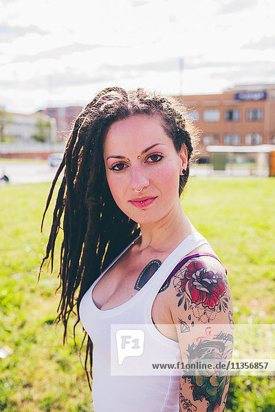 Portrait of tattooed young woman in urban park
