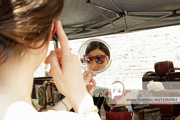 Spiegelbild einer Frau beim Anprobieren einer Sonnenbrille am Marktstand  Mailand  Italien