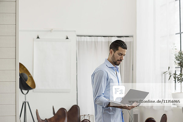 Businessman using laptop while standing at table in office