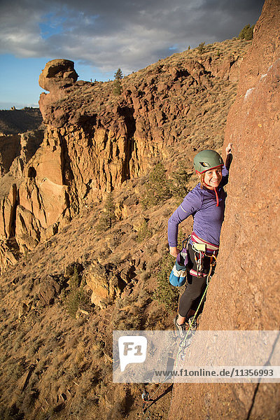Woman rock climbing looking at camera smiling