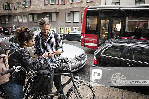 Freunde mit Fahrrädern beim Telefonieren über die Stadtstraße
