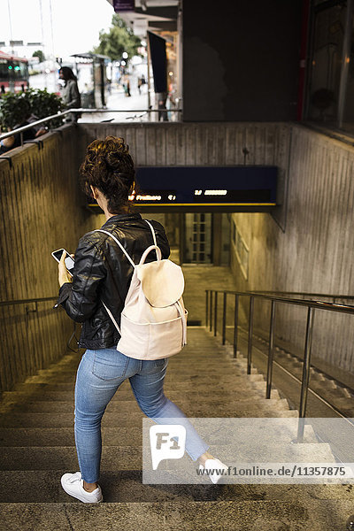 Rear view of woman walking down steps at subway station
