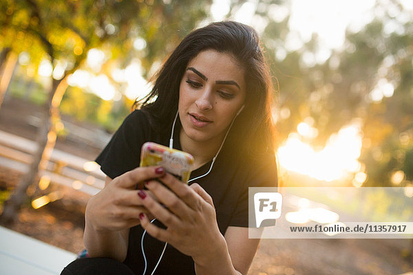 Junge Frau  im Freien  trägt Kopfhörer  hält Smartphone