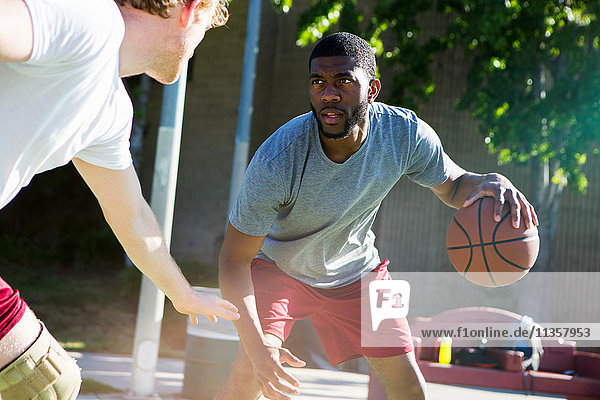 Two men playing basketball on outdoor court