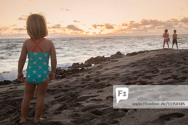 Mädchen schaut bei Sonnenaufgang aufs Meer hinaus  Blowing Rocks Preserve  Jupiter Island  Florida  USA