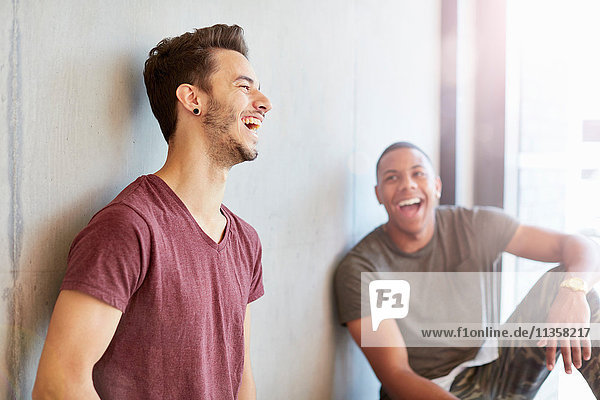Two young male students in study space laughing at higher education college