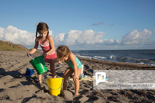 Zwei Schwestern spielen mit Spielzeugkübeln am Strand  Blowing Rocks Preserve  Jupiter Island  Florida  USA