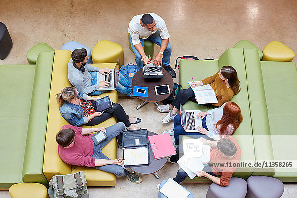 Overhead view of seven male and female students brainstorming in higher education college study space