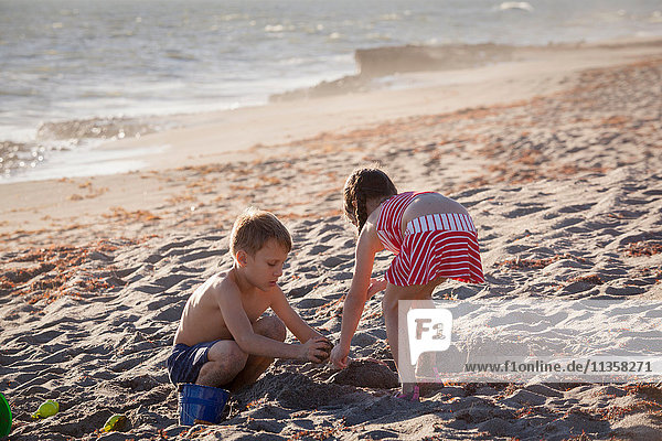 Junge und Schwester spielen mit Sand am Strand  Blowing Rocks Preserve  Jupiter Island  Florida  USA