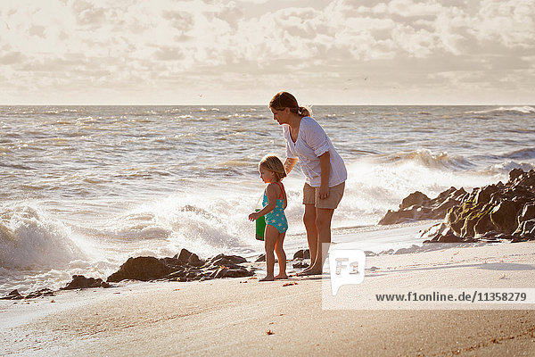 Mature woman and daughter watching splashing waves  Blowing Rocks Preserve  Jupiter Island  Florida  USA