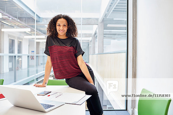 Porträt einer jungen Designerin  die im Designstudio am Schreibtisch sitzt