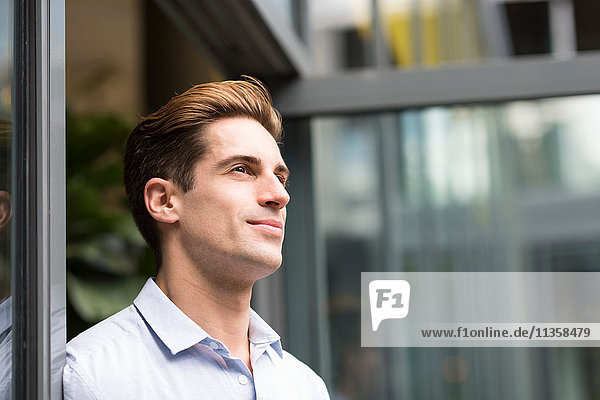 Young businessman leaning against office doorway  London  UK