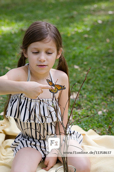Mädchen hält Monarch-Schmetterling am Finger