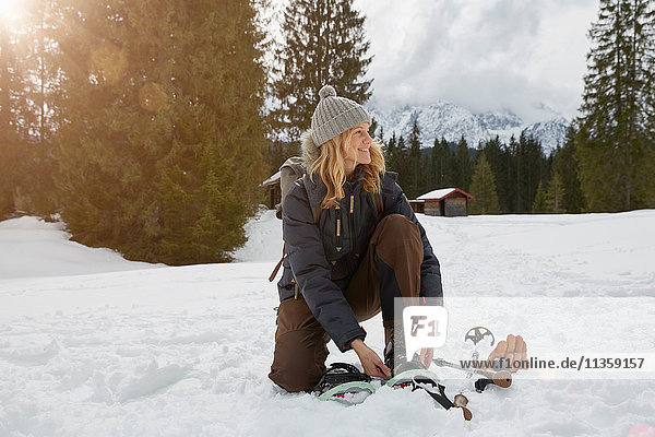 Mature woman putting on snow shoes in snowy landscape  Elmau  Bavaria  Germany