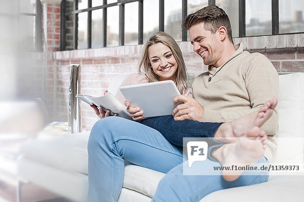 Couple at home  relaxing on sofa  looking at digital tablet