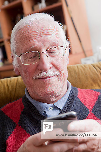 Senioren-Mann mit Handy zu Hause