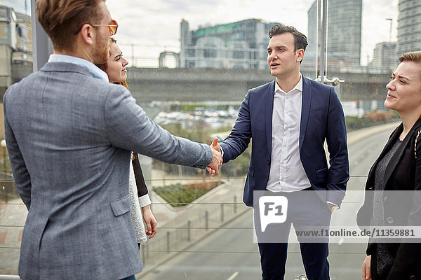 Businessmen and women shaking hands on city footbridge  London  UK