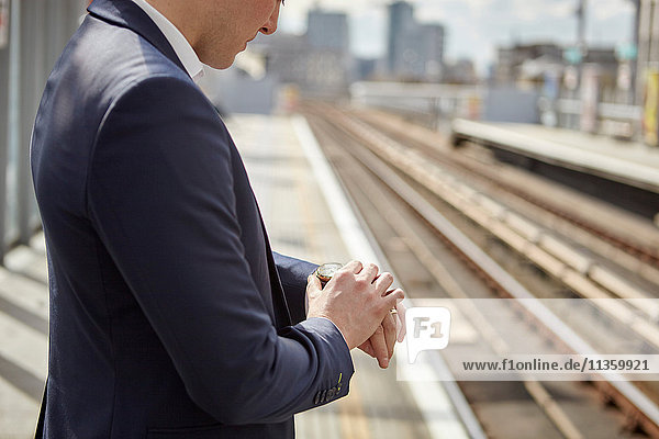 Cropped shot of businessman checking watch at train platform  London  UK