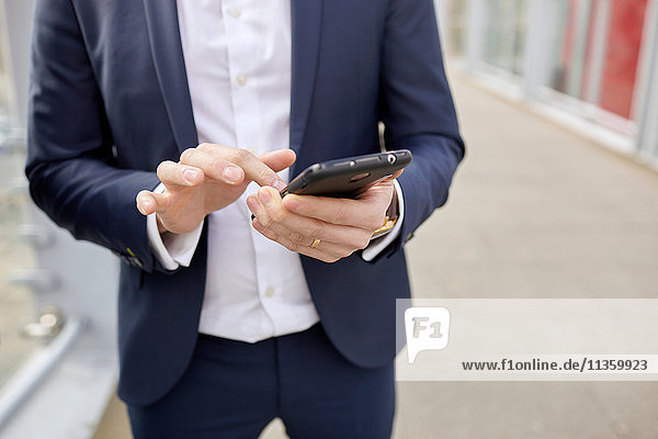 Mid Abschnitt der Geschäftsmann auf Fußgängerbrücke SMS auf Smartphone  London  UK