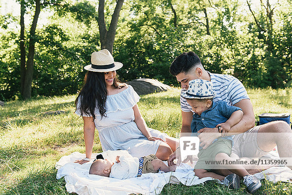 Eltern und Kleinkind betrachten den kleinen Sohn auf einer Picknickdecke im Pelham Bay Park Bronx New York USA