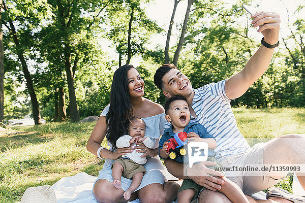 Eltern mit Säuglingen und Kleinkindern nehmen Smartphone-Selfie in Pelham Bay Park, Bronx, New York, USA