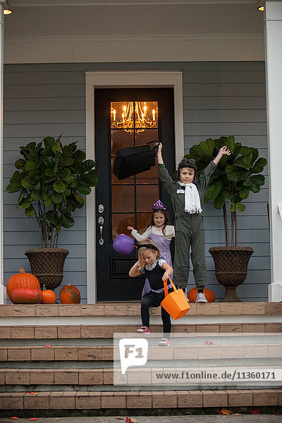 Boy and sisters trick or treating celebrating on porch