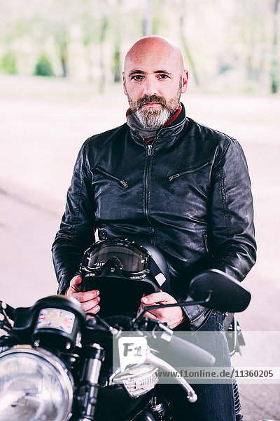 Portrait of mature male motorcyclist sitting on motorcycle