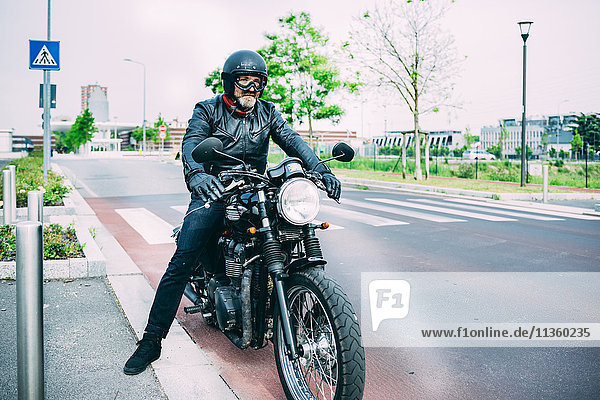 Erwachsener Motorradfahrer sitzt auf dem Motorrad auf der Straße