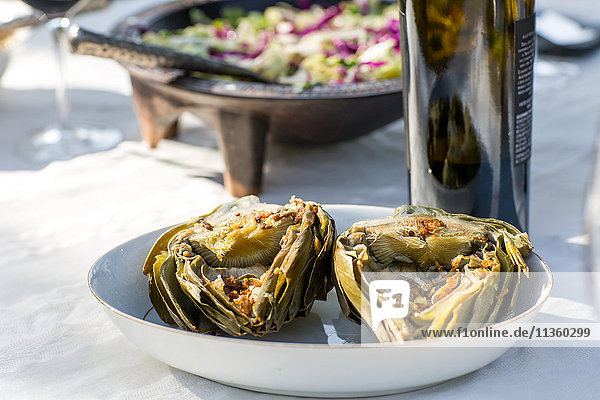 Party garden table with wine bottle and baked artichokes