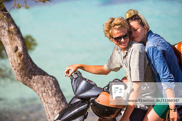 Romantisches junges Paar sitzt auf einem Moped an der Küste  Mallorca  Spanien