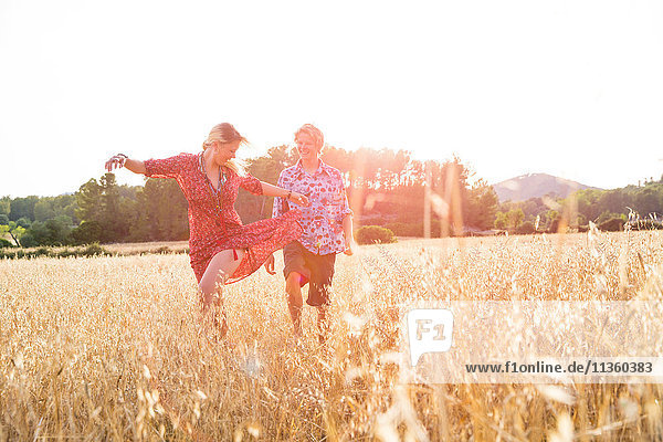 Junge Frau mit Freund tanzt im Weizenfeld  Mallorca  Spanien