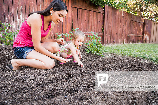 Mutter und junge Tochter pflanzen Samen im Garten