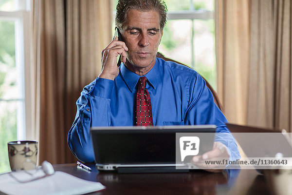 Mature man at home  using laptop and smartphone